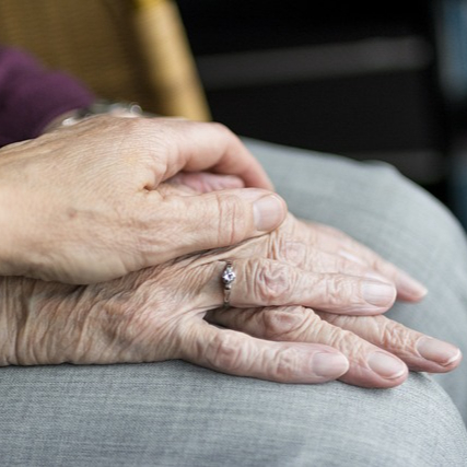 A younger person with their hand placed atop an elderly person's hand