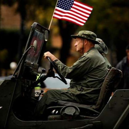 U.S. veteran driving an open-air Jeep with an American flag on it