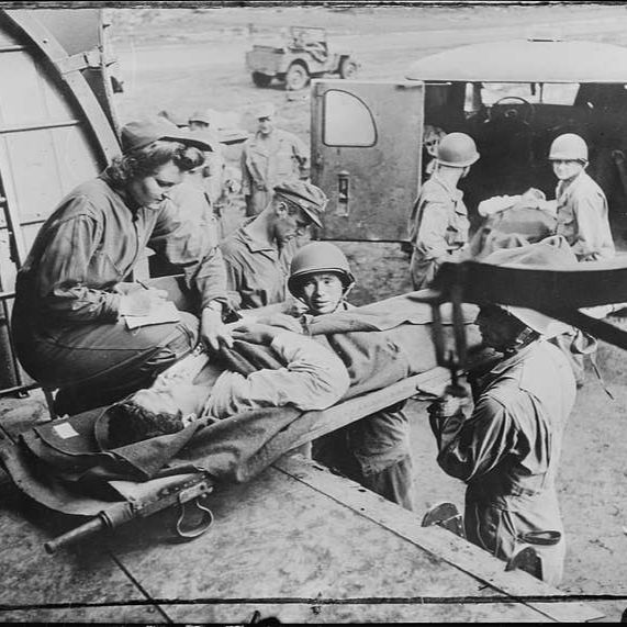  United States Army Nurse flies with wounded. Lieutenant Mae Olson (left), of the United States Army Nurses Corps, takes the name of a wounded American soldier as he is placed aboard a hospital plane of a United States Army Air Force aerial evacuation unit on Guadalcanal in the Solomon Islands.