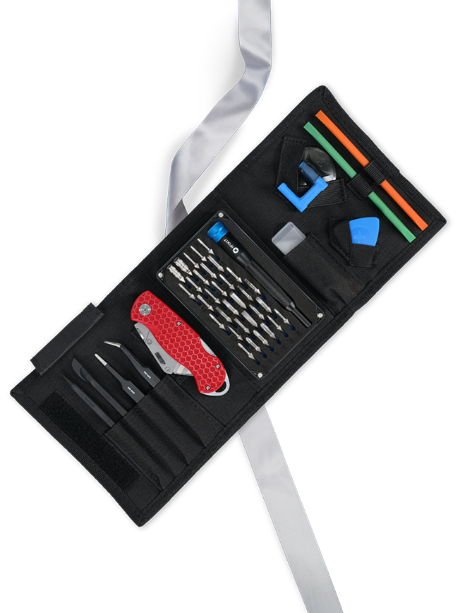 The JerryRig Toolkit tool roll opened on top of a silver ribbon, to reveal the red Razor knife and other components inside