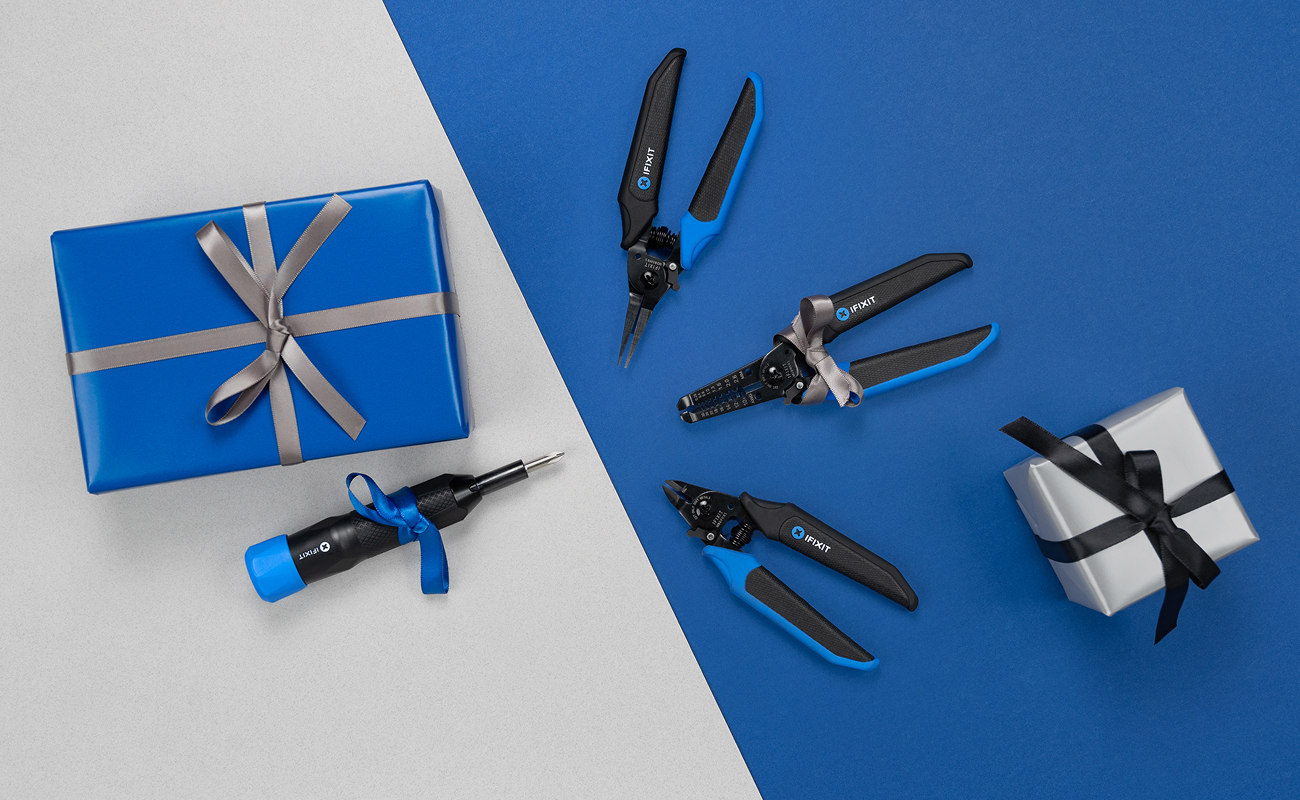 Image showing Fixit Mandible pliers arranged on a blue and light grey background alongside a wrapped silver gift and a wrapped blue gift. The Narwhal 6-in-1 Driver lies below a blue gift box.
