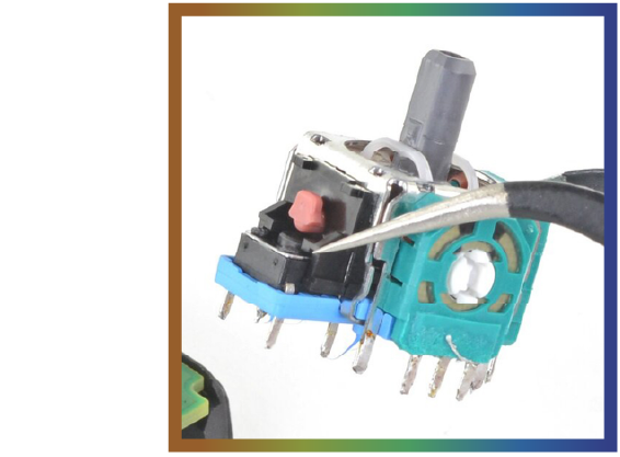 Close-up of a game controller joystick module being pried with tweezers.