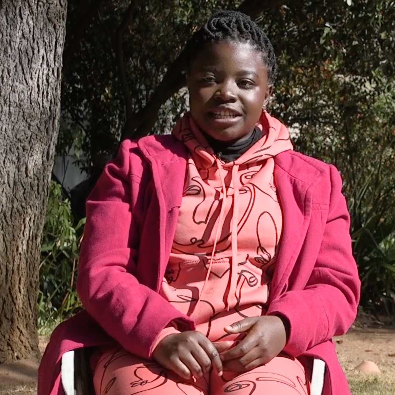 Photo of a young lady in a pink coat outside. 