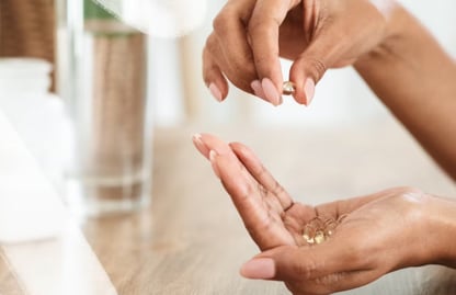 One hand putting supplements in another hand