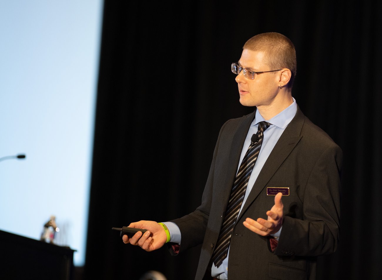 Photo of Dr. Gleb presenting at a conference dressed in a suit and tie