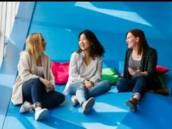 Three students sitting on the blue stairs in the Student Learning Centre