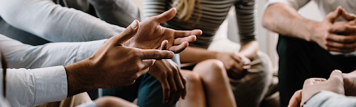 Tha hands of a diverse group of people, sitting in a circle and gesturing in discussion. Tha hands of a diverse group of people, sitting in a circle and gesturing in discussion.