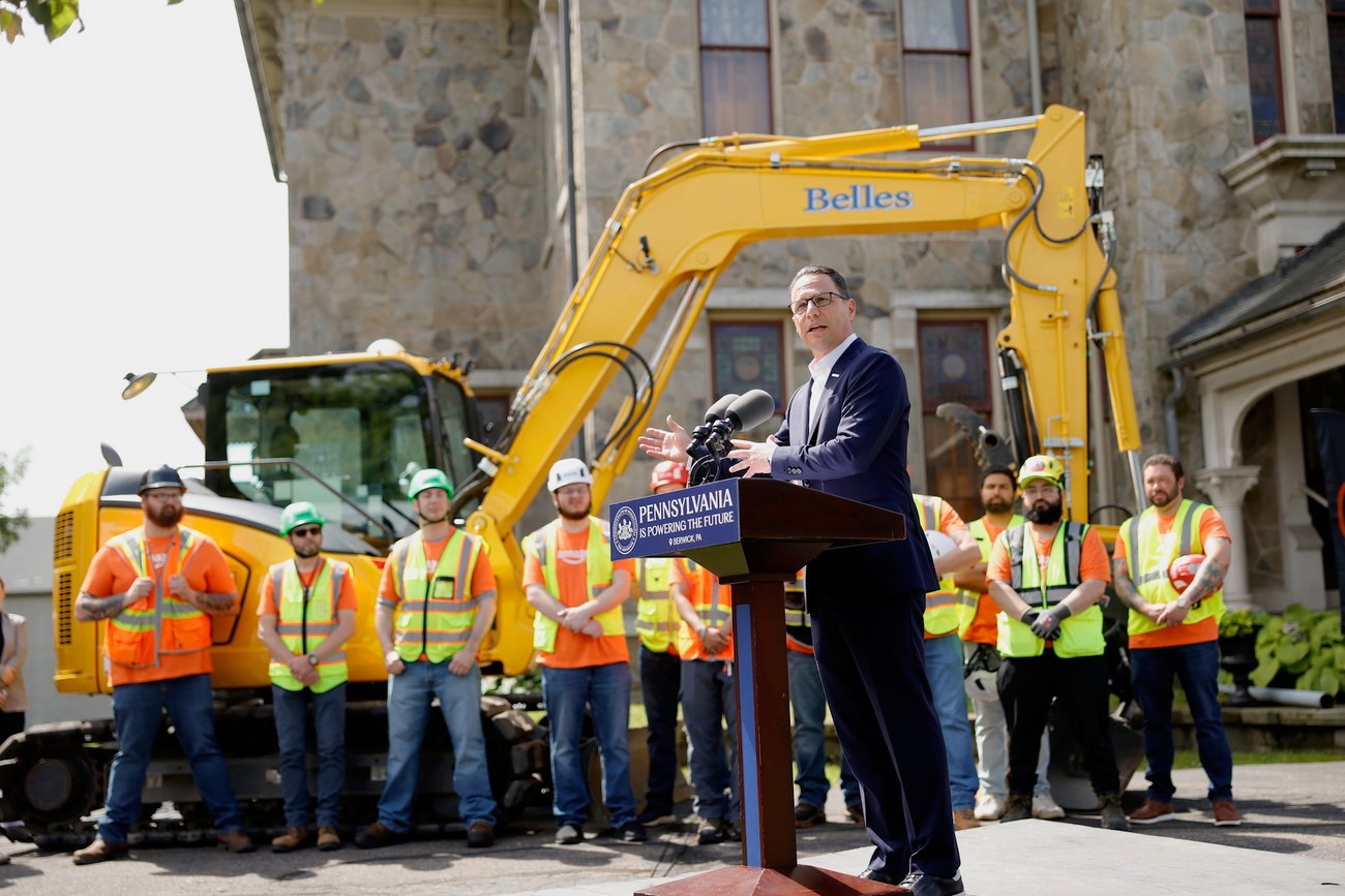 Gov. Josh Shapiro stands in front of construction workers and equipment