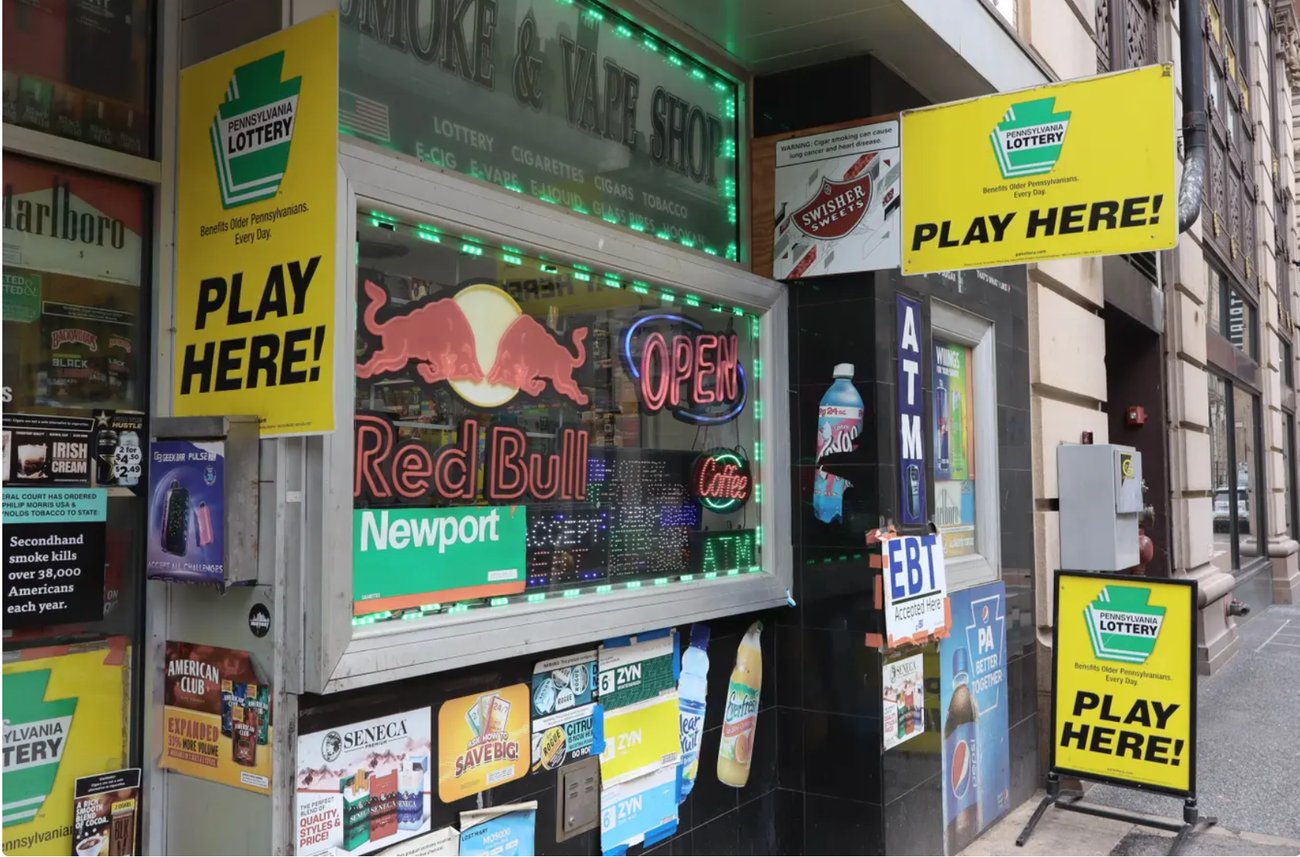 A convenience storefront with signs for the state lottery and various products