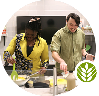 Two people smile as they cook together in a kitchen.