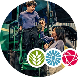 A mother helps her child descend from a tractor at the Canada Agriculture and Food Museum.