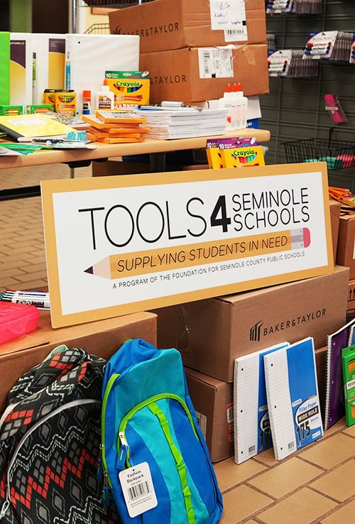 Sign saying "Toos 4 Seminole Schools" around school supplies