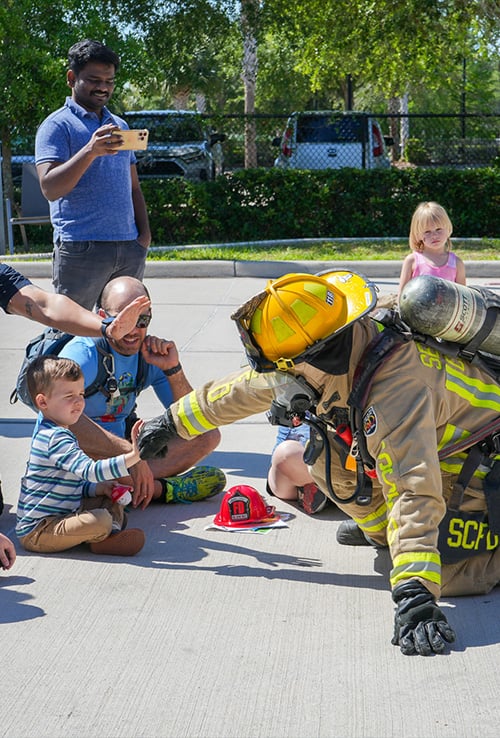 Kid fist bumping a firefighter in gear