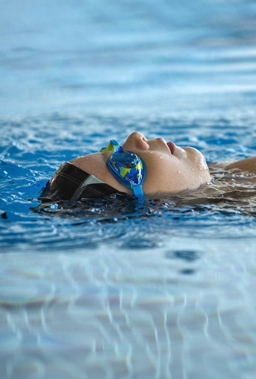 person floating in pool wearing swim googles