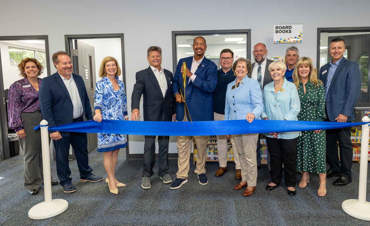 County and city officials cutting a ribbon inside the library County and city officials cutting a ribbon inside the library