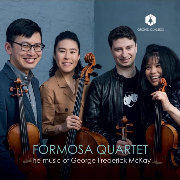 Four musicians with their instruments dressed casually smile