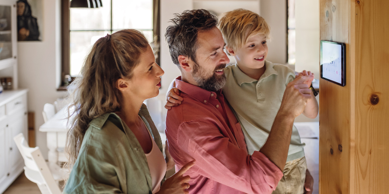 Family adjusting a smart thermostat Family adjusting a smart thermostat