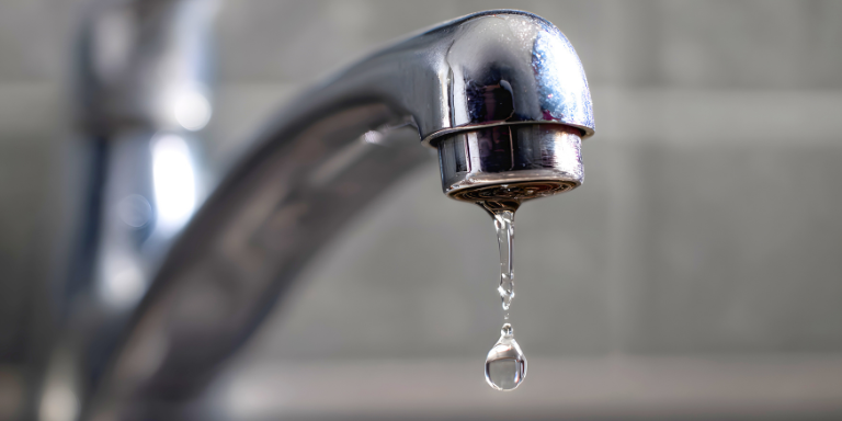 Photo of a drop of water coming down a faucet.