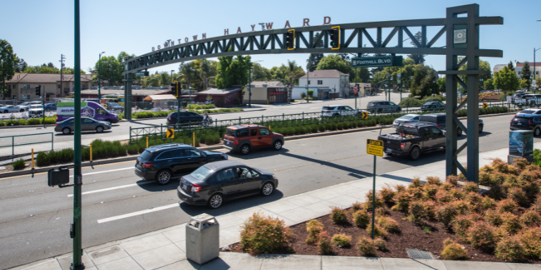 Photo of Mission Boulevard, a two way street with three lanes on each side and a large arching sign reading Downtown Hayward. Photo of Mission Boulevard, a two way street with three lanes on each side and a large arching sign reading Downtown Hayward.