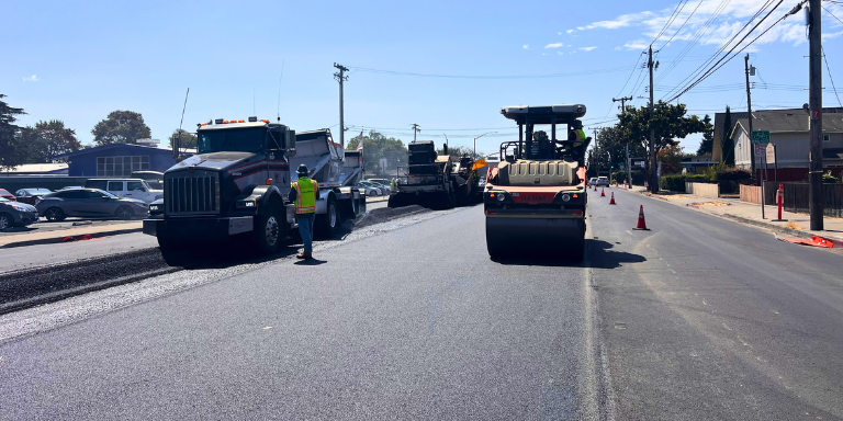 Photo of trucks and a roller machine paving a street in Hayward. Photo of trucks and a roller machine paving a street in Hayward.