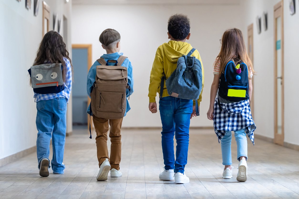 Four kids walking into school, shot from behind