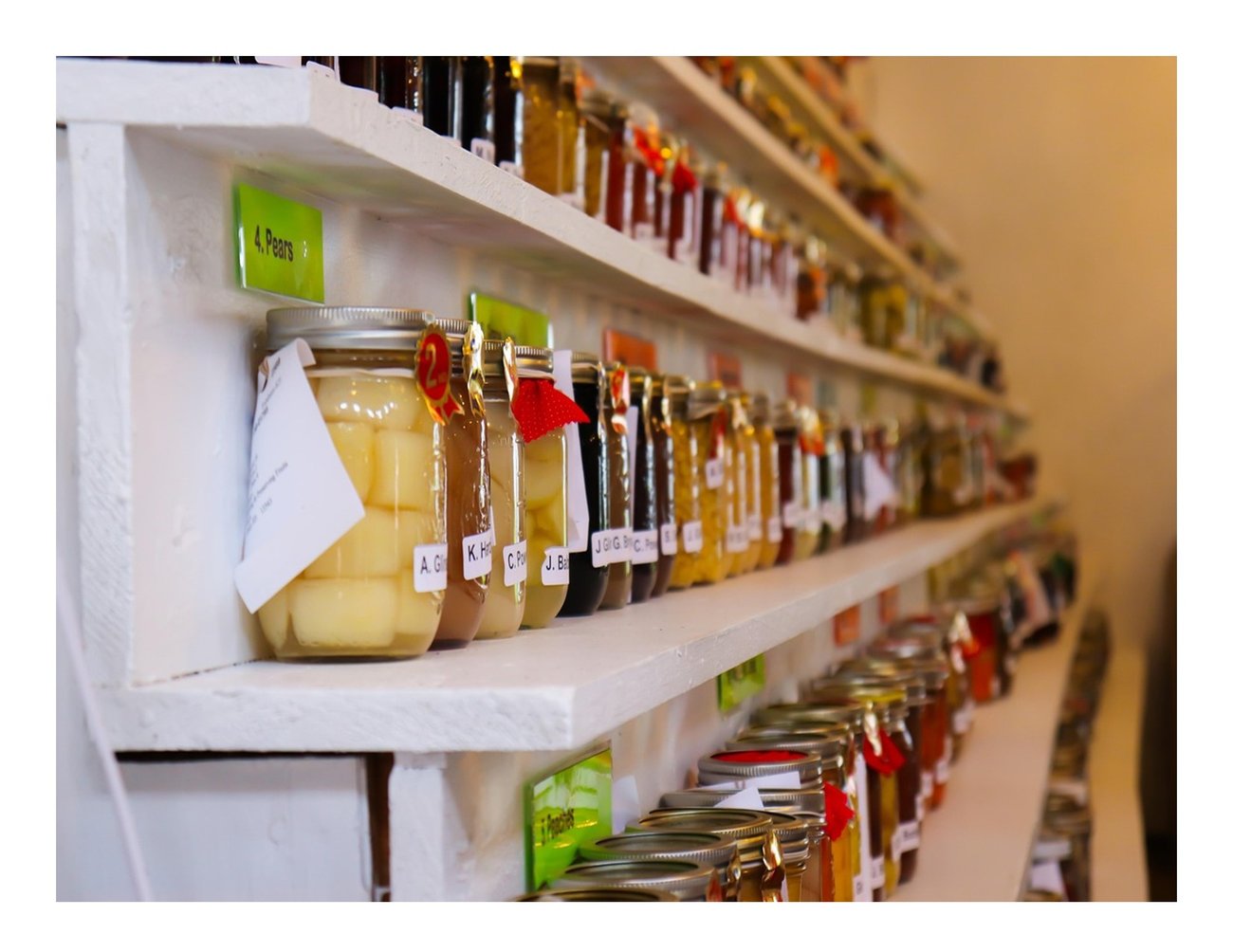 various canned good sitting on white shelves looking longward