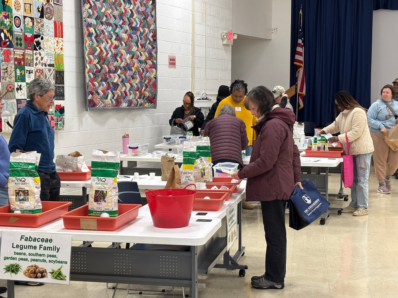Photo from NC Cooperative Extension Guilford County Center Open House. People conversing and visiting information tables in the lobby. 