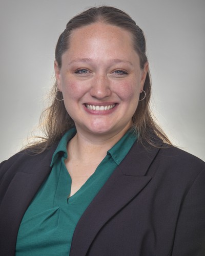Rachel Blazzard, Extension Agent, Community & Rural Development & 4-H Youth Development wearing a green shirt, black jacket, smiling with a neutral background.