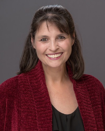Tiffany Hancock County Extension Marketing and Media Support Specialist is wearing a burgundy sweater with black blouse smiling against a neutral background.