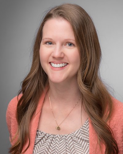 Tara Gregory Extension Agent, Family and Consumer Sciences agent is wearing a beige and white top with a pink sweater, a necklace and smiling with a neutral background.