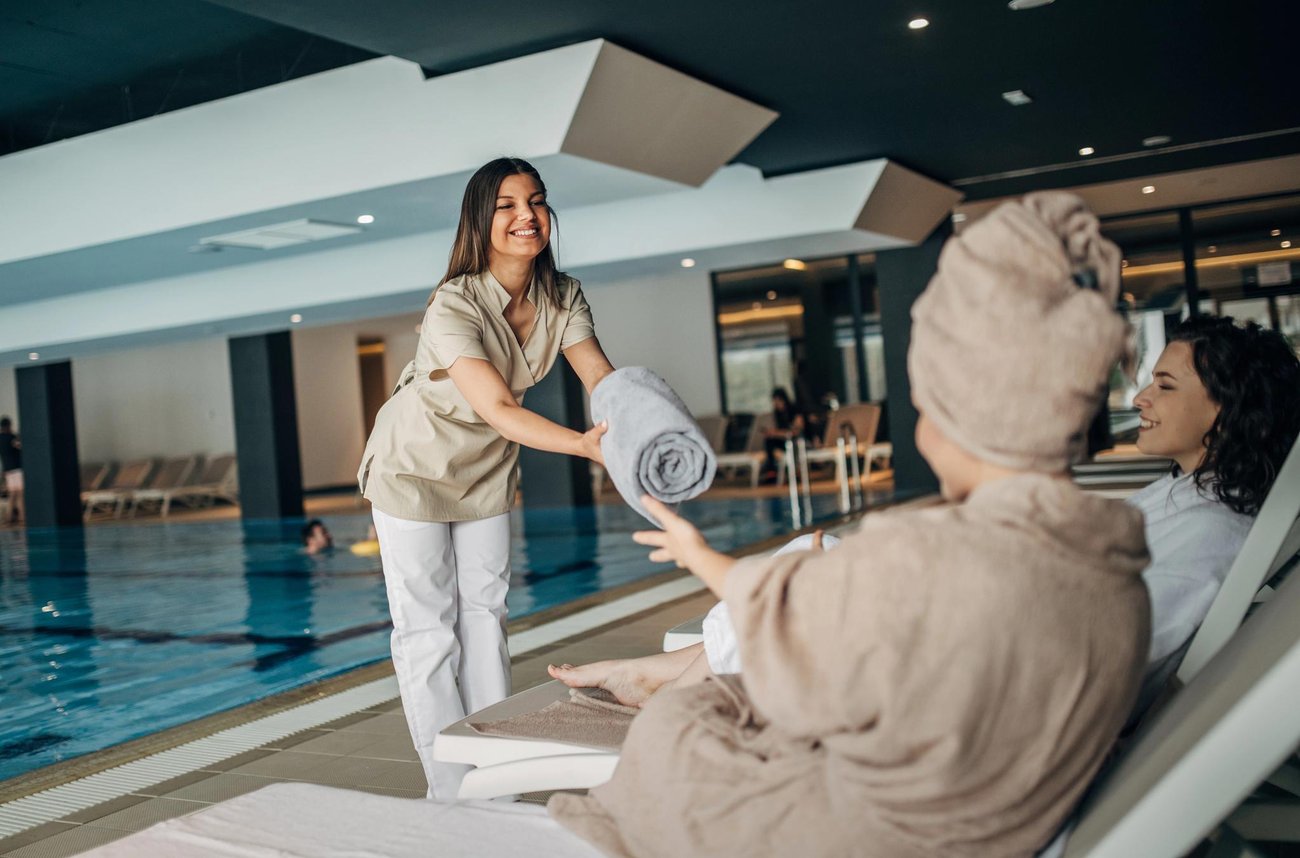 Employee handing towels to guests near pool/spa