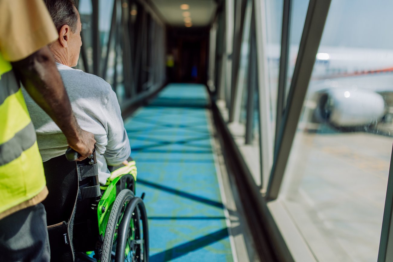 A traveler's wheel chair is pushed by an airport employee.