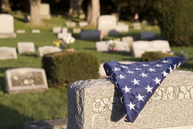Headstone with a folded American flag laying on top.