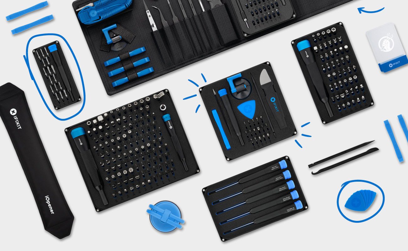 Flat lay image on a light grey background displaying various iFixit tools, including bit sets, toolkits, opening tools, tweezers, and spudgers, arranged neatly with white doodle highlights.