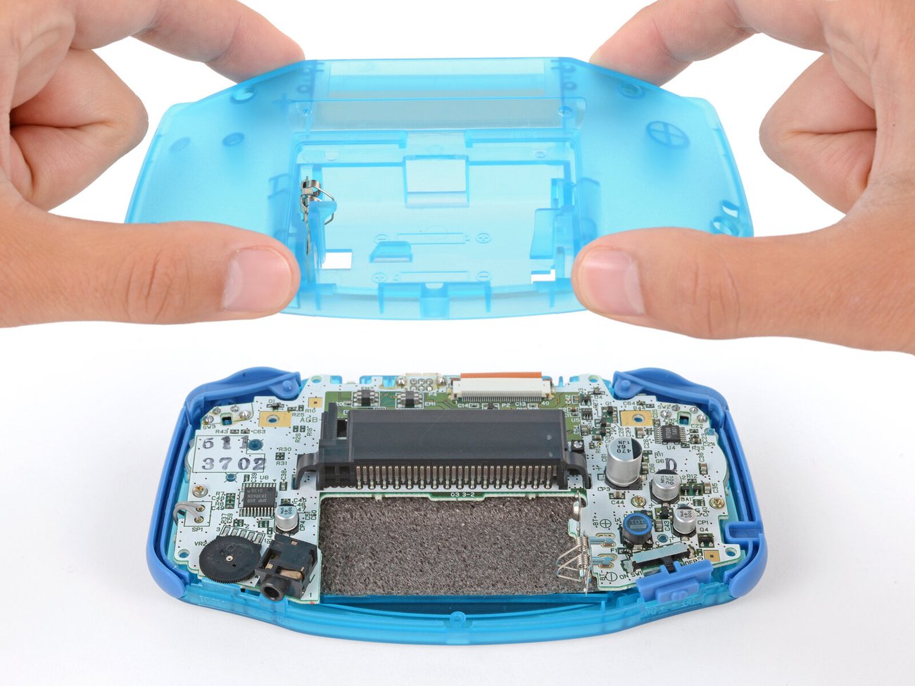 Hands lifting the clear blue case of a Game Boy Advance