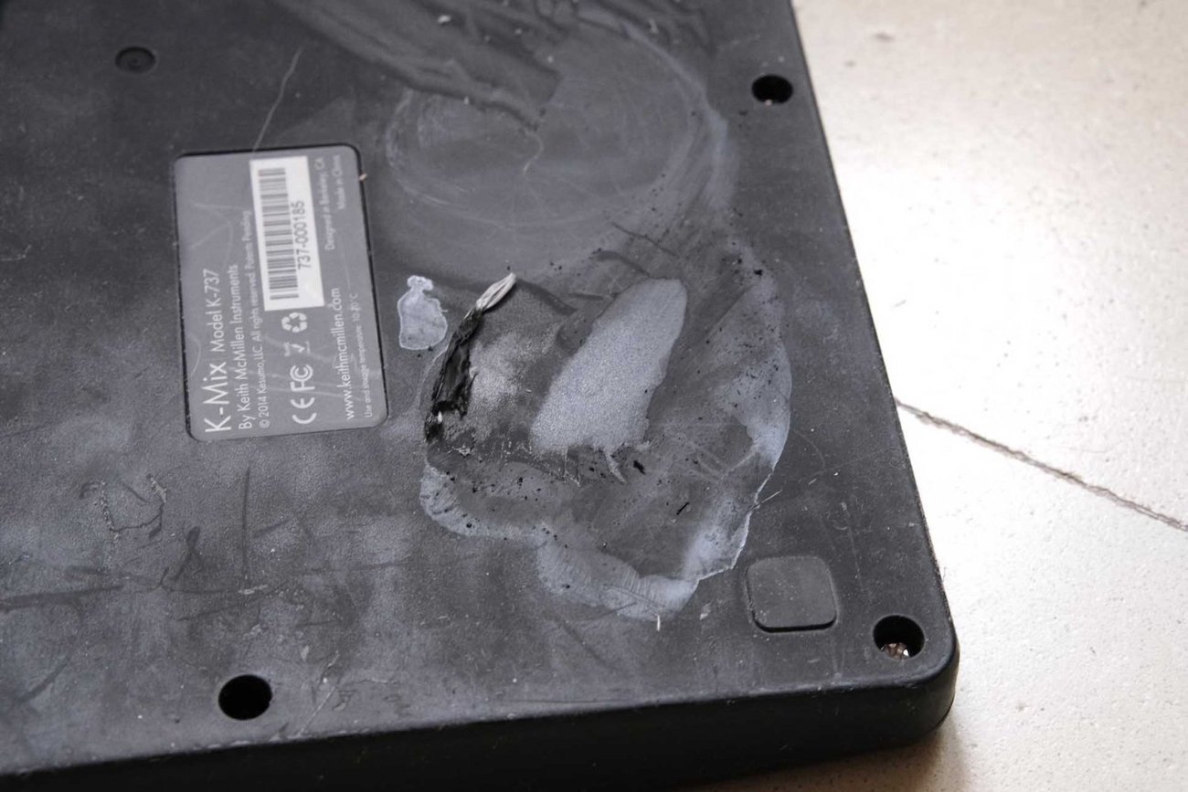 Laptop keyboard with a sticky smudge, being wiped away by a yellow microfiber cleaning cloth.