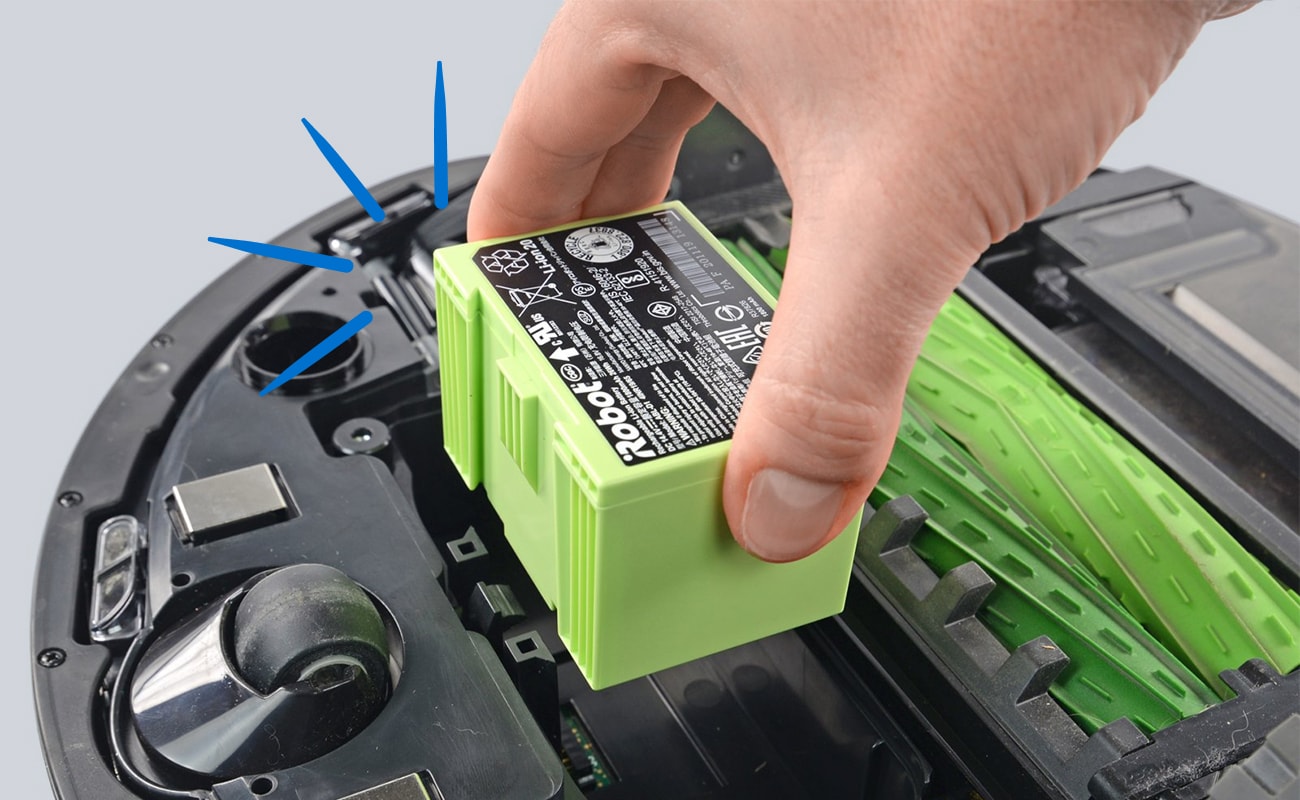 A close-up shows a hand lifting a bright green battery out of an opened robot vacuum, with blue marker lines highlighting an internal component on the left.
