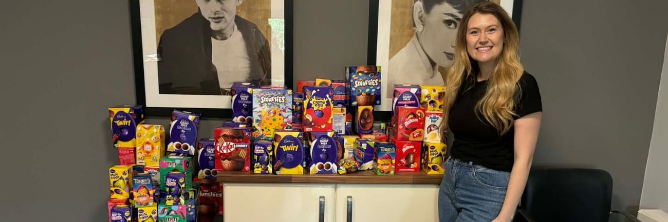 Amber Coates, Community Fundraiser standing smiling next to display of easter eggs