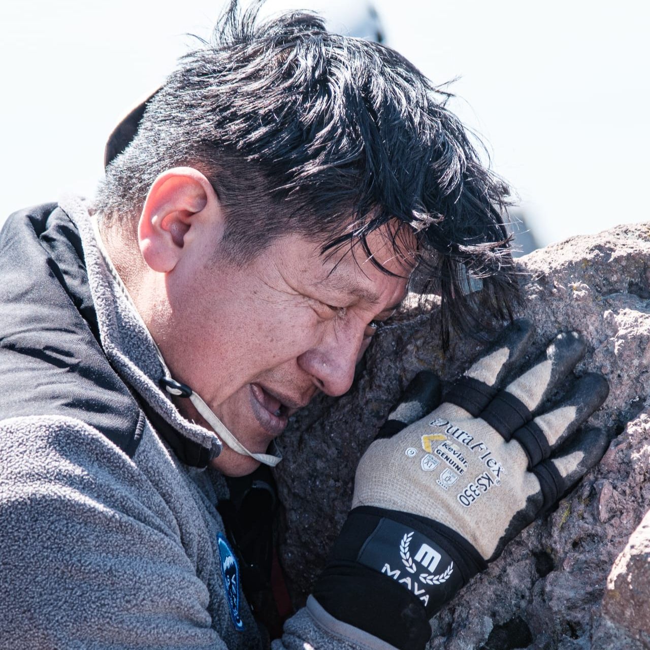 image of man hugging a rock after climbing a mountain