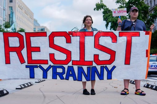 A photo of people at a protest holding a banner reading "RESIST TYRANNY"