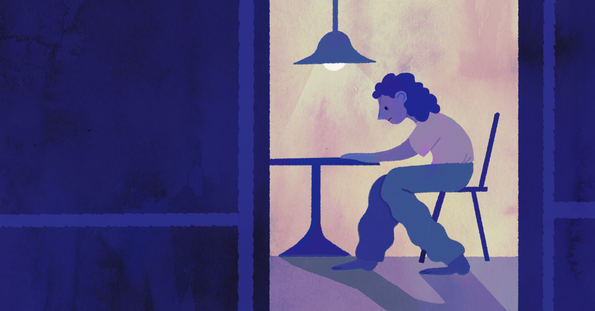 Sad person sitting alone at a table at night.