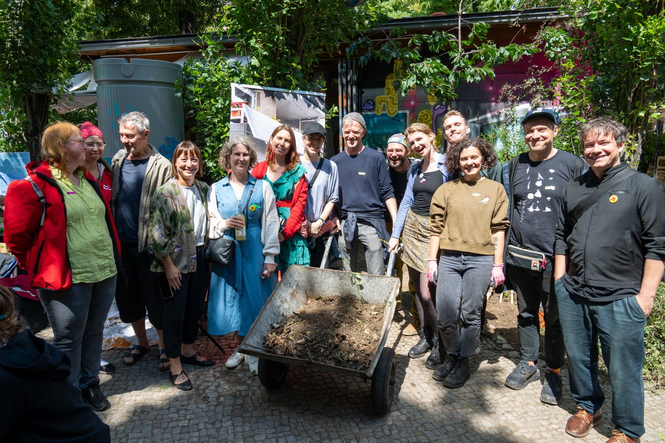 Foto von einer Gruppe von Menschen, die um eine Schubkarre herum stehen.