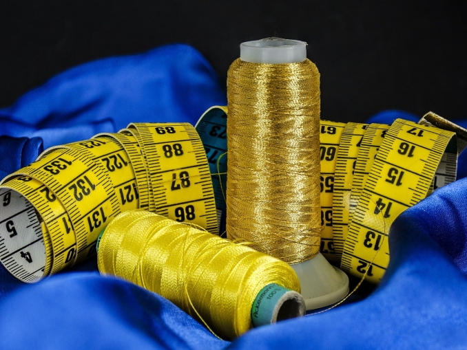 Foto auf dem Nähgarn, Stoff und ein Maßband zu sehen ist..