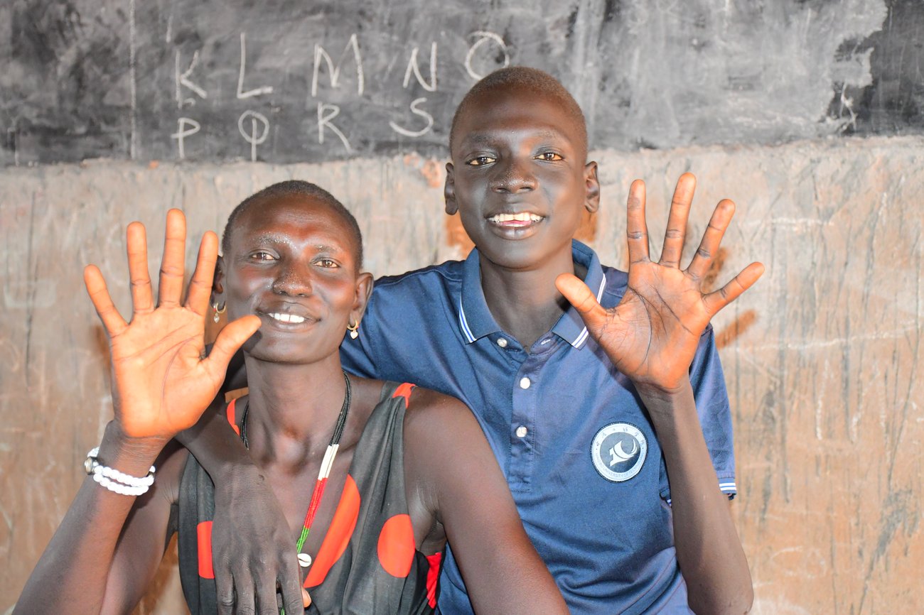 Image: Mauen Makuac Riak, a 15-year old student, and his mother smile together in a classroom, after taking part in a Sign Language training. “I want to continue my studies to become a teacher like one of the Light for the World facilitators who have been
training me in sign language,” says Mauen. Copyright: Nema Juma / Light for the World 