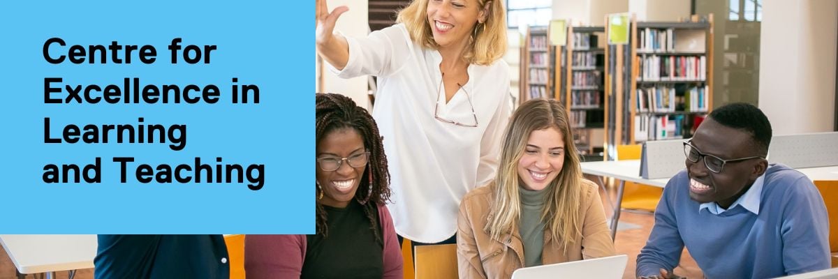 A educator stands, offering a high five to a student sitting alongside three smiling peers in a library setting. 