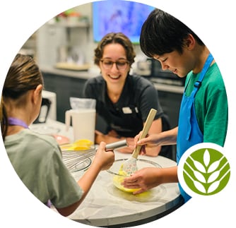 A guide assists two children in the Demonstration Kitchen.