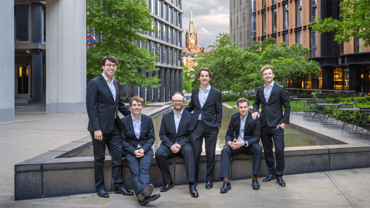 Casual portrait of The Gesualdo Six, each in a dark suit with a light shirt, no tie, in a plaza in London, St. Pancras railway station visible in background. Casual portrait of The Gesualdo Six, each in a dark suit with a light shirt, no tie, in a plaza in London, St. Pancras railway station visible in background.