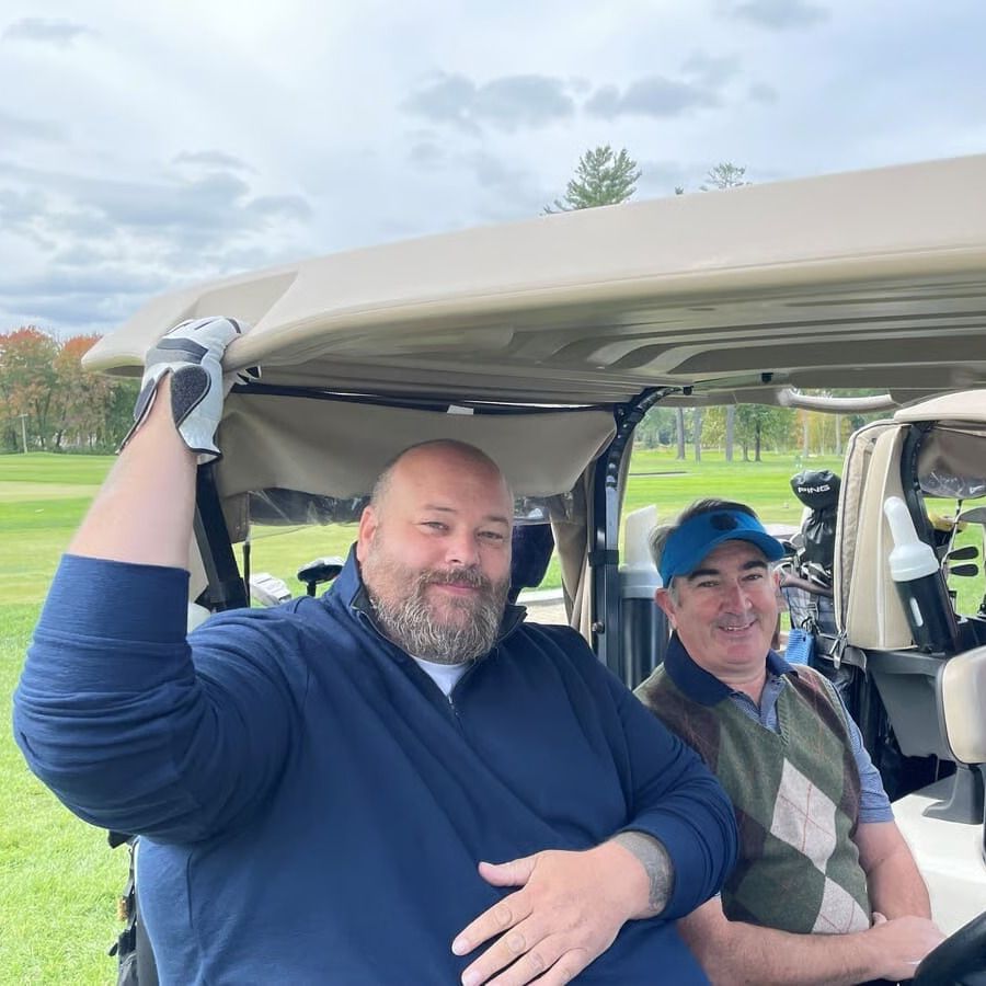 Two men cooking over a grill outside.