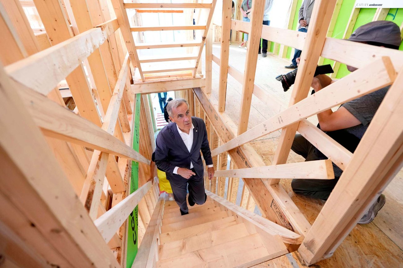 A photo of Prime Minister Mark Carney walking up the stairs of a building that is under construction.
