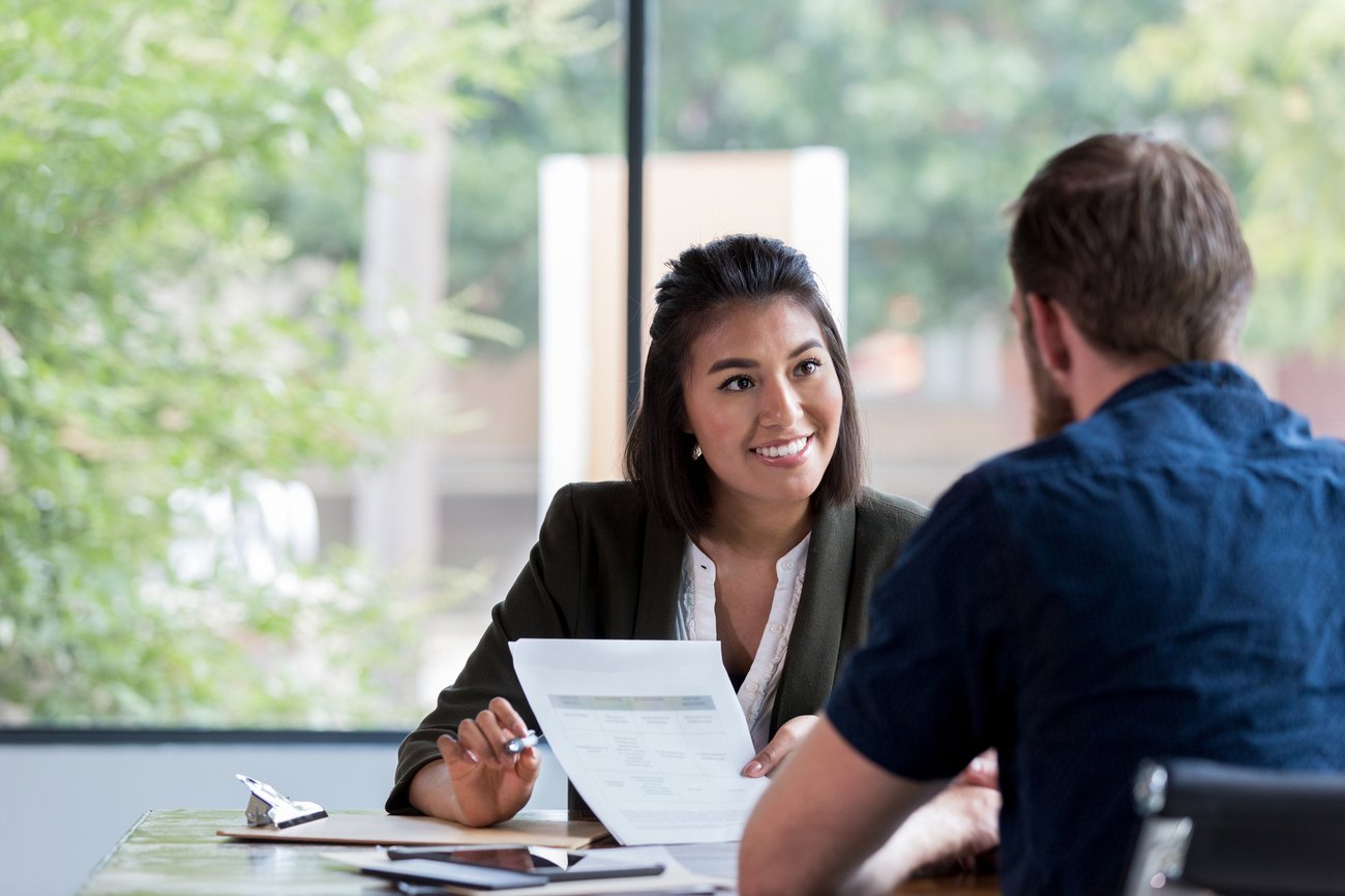 businesswoman smiles while showing a document to a male associate